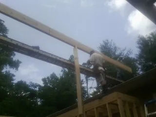Carpenter setting a ridge beam over a new addition frame — Ice Dam Removal by Roofing Brothers in Albertson