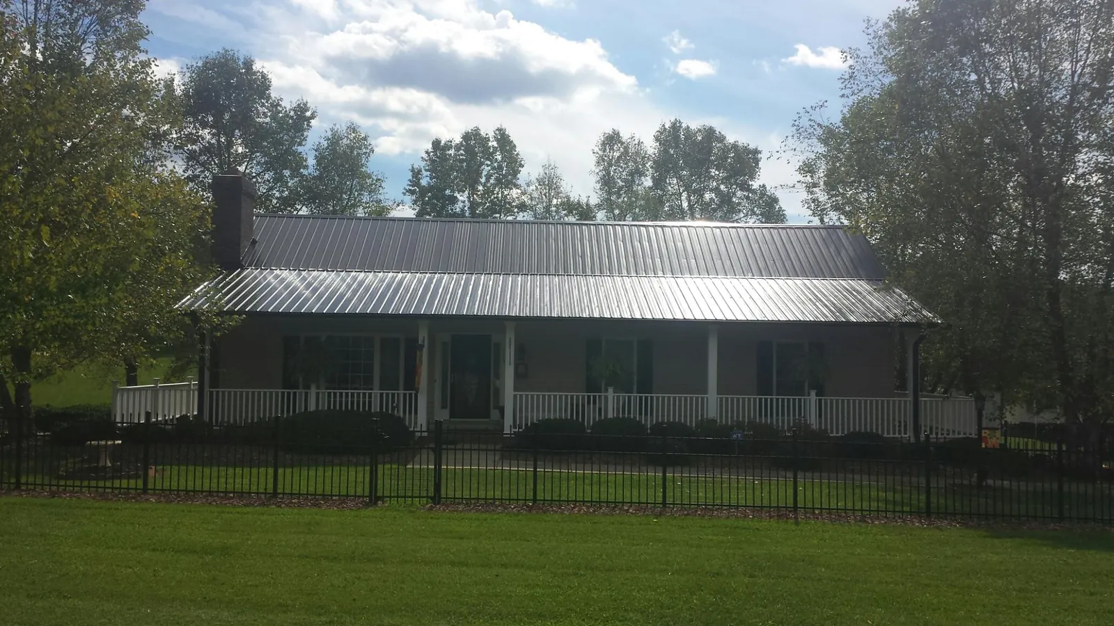 Gray metal roof on a brick ranch with a full width front porch — Gutter Guard Installation work by our crew in Albertson