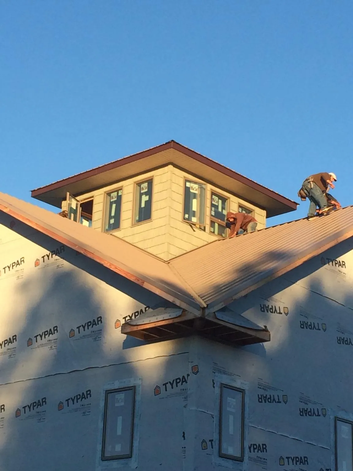 Roofers working around a rooftop cupola on a new metal roof at sunset — Roof Waterproofing in Albertson by Roofing Brothers